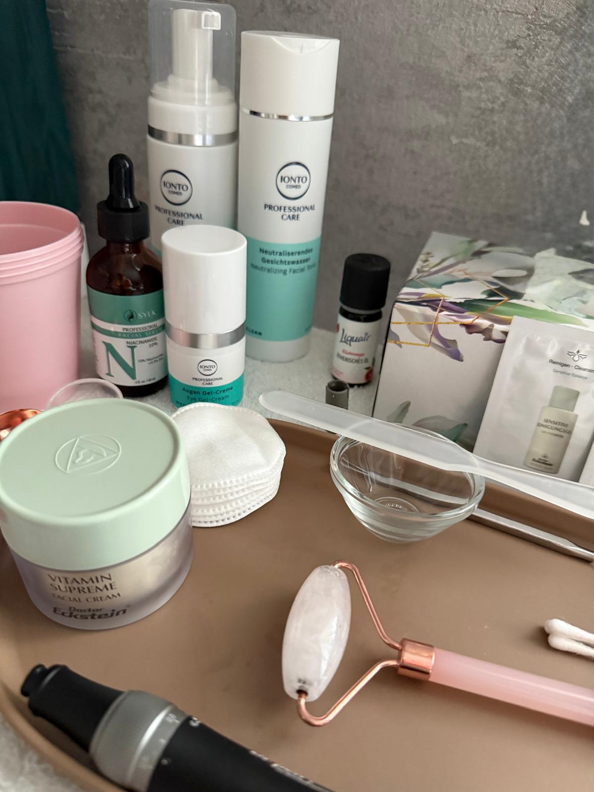 Mehrere Kosmetikprodukte in hellen Farben stehen sauber arrangiert auf einem Tablett